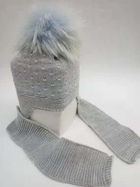 Gorro gris con motas azules con bufanda unida y pompóm de pelo natural.